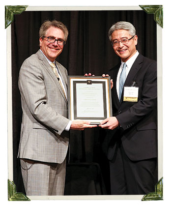 Dean Eric Johnson presenting the 2015 Distinguished Alumni Award to Heiki Miki, MBA'96